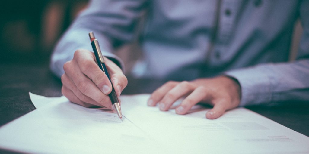 Photographie d'un homme écrivant sur du papier avec son stylo